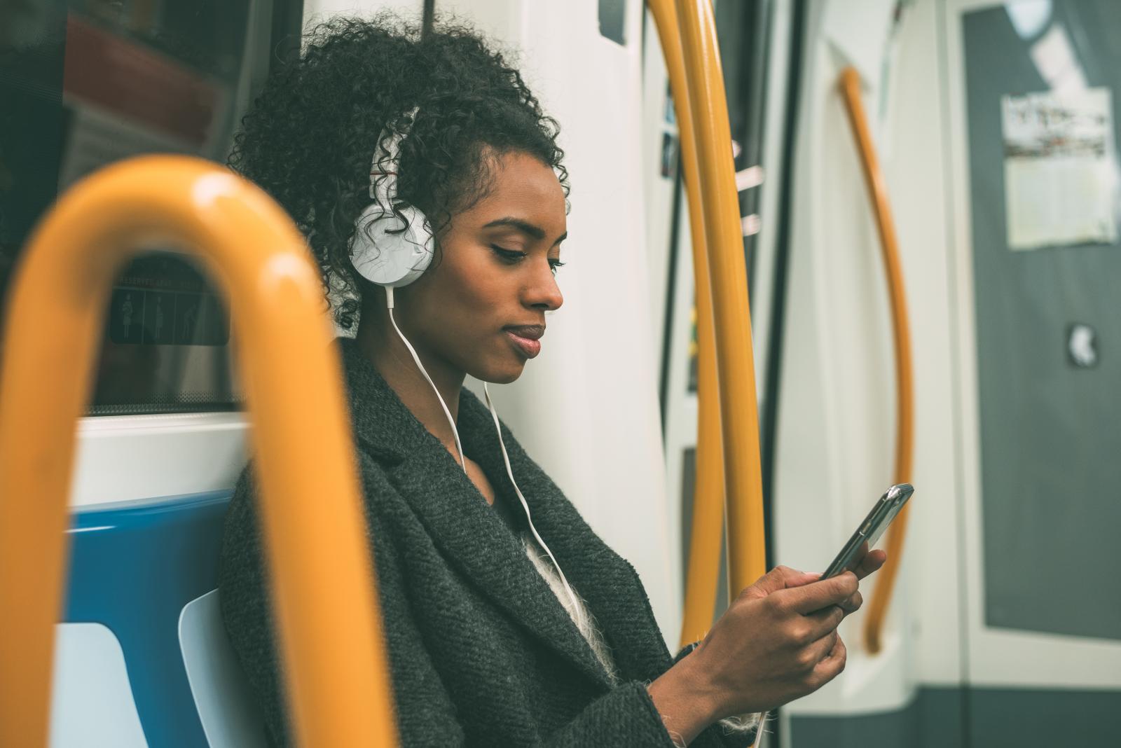 Woman on tube with phone and headphones