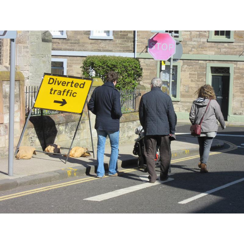 A family with a pram are forced onto the road by a sign