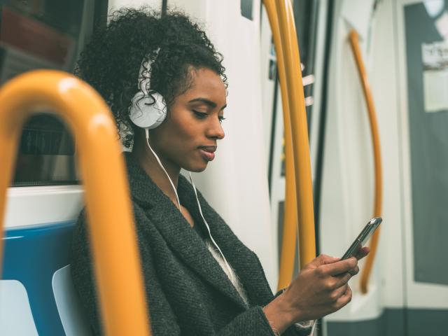Woman on tube with phone and headphones